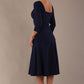 Model wearing the Rowan dress in navy blue, showing the square neckline and ruched bodice, side back view