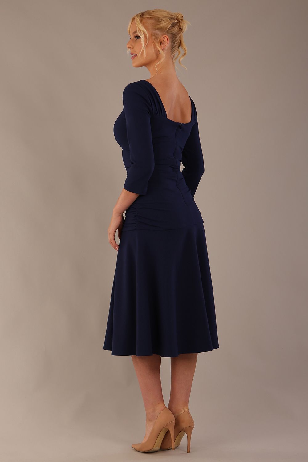 Model wearing the Rowan dress in navy blue, showing the square neckline and ruched bodice, side back view