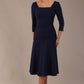 Model wearing the Rowan dress in navy blue, showing the square neckline and ruched bodice.