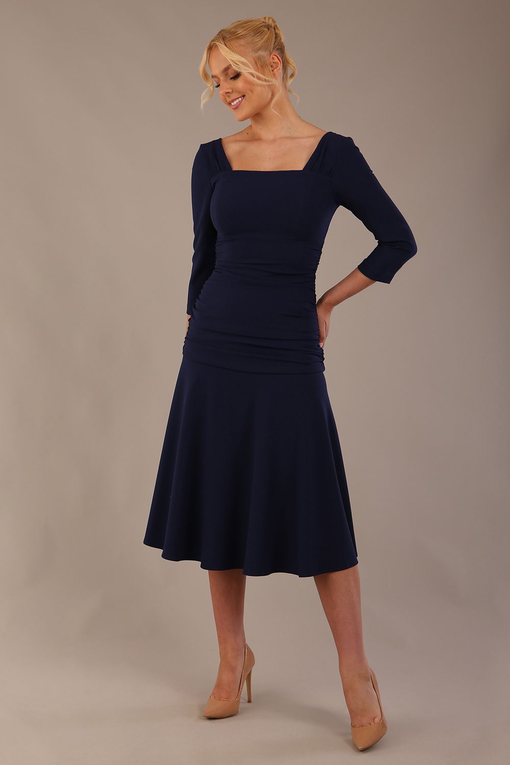 Model wearing the Rowan dress in navy blue, showing the square neckline and ruched bodice.