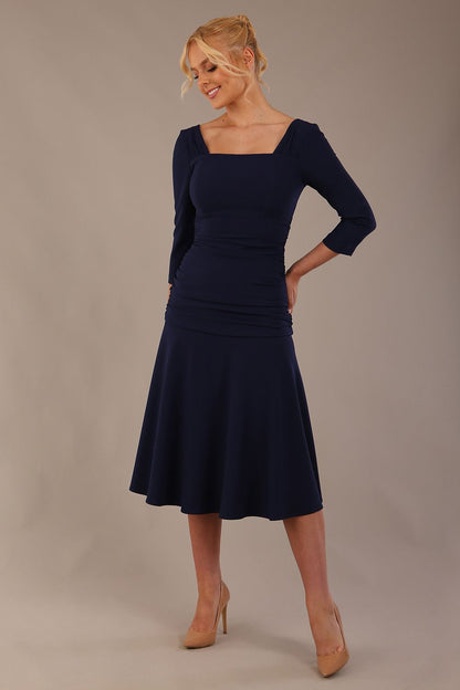 Model wearing the Rowan dress in navy blue, showing the square neckline and ruched bodice.
