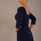 Model wearing the Rowan dress in navy blue, showing the square neckline and ruched bodice, close up back view