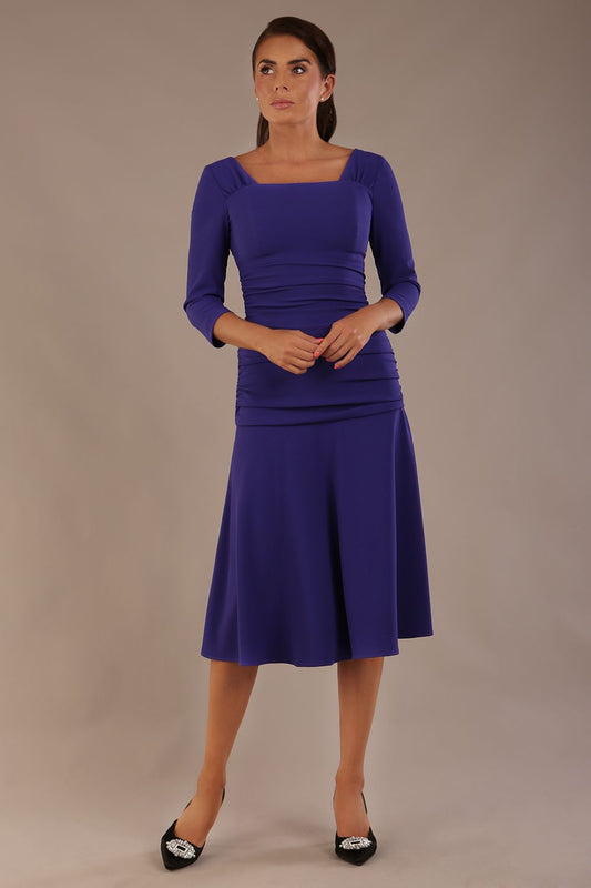 Model wearing the Rowan dress in spectrum indigo, showing the square neckline and ruched bodice.