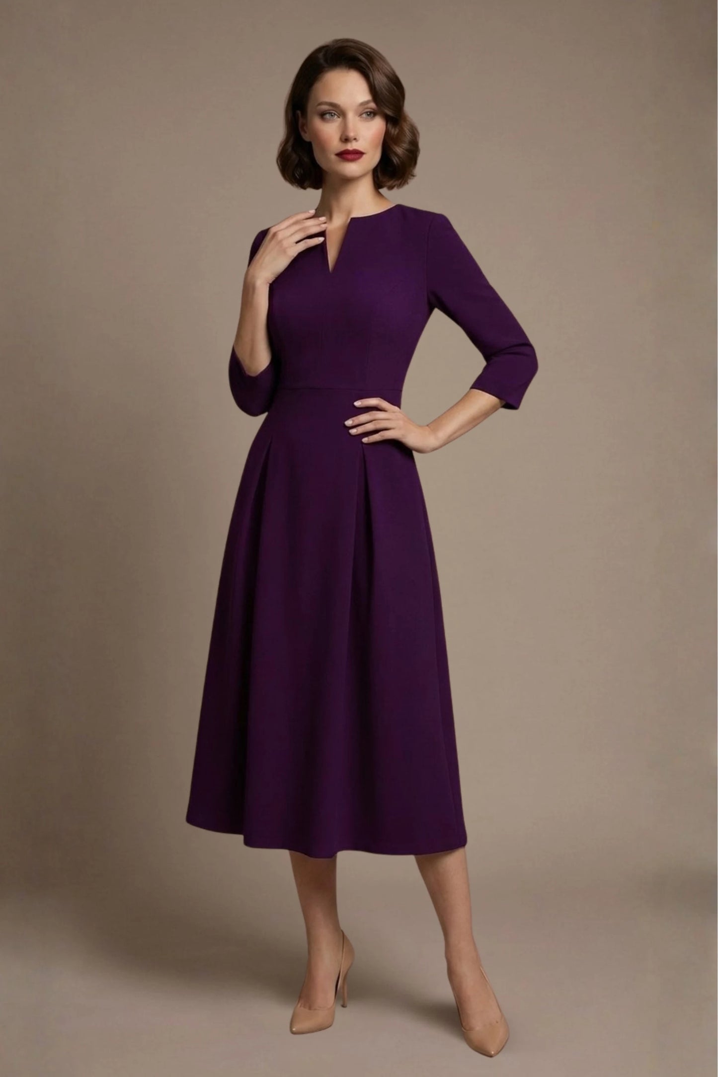 Woman wearing a diva catwalk Amanda Pleated a-line dress in a magenta pink colour against a beige background (Purple)