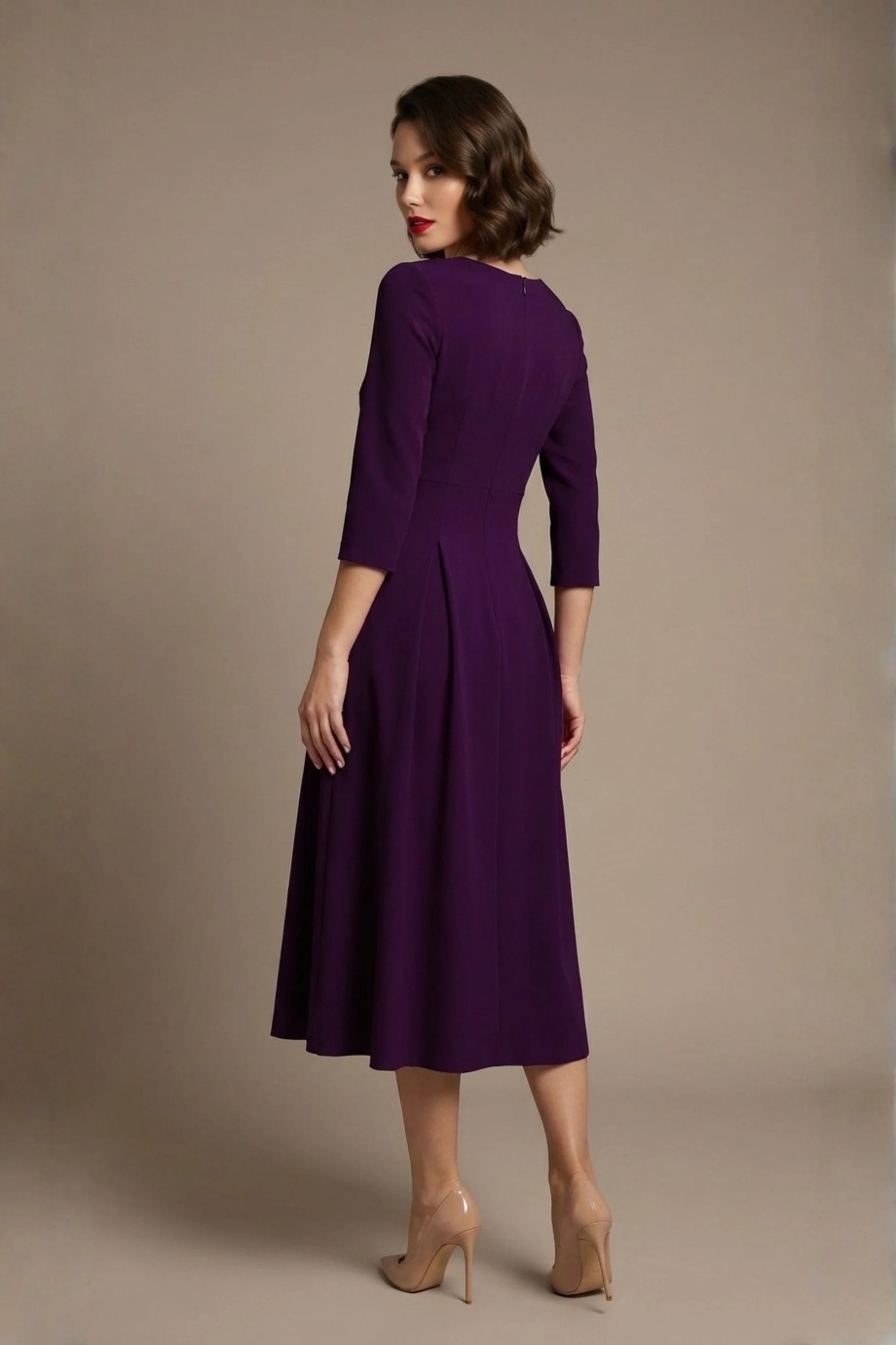 Woman wearing a diva catwalk Amanda Pleated a-line dress in a magenta pink colour against a beige background (Purple)