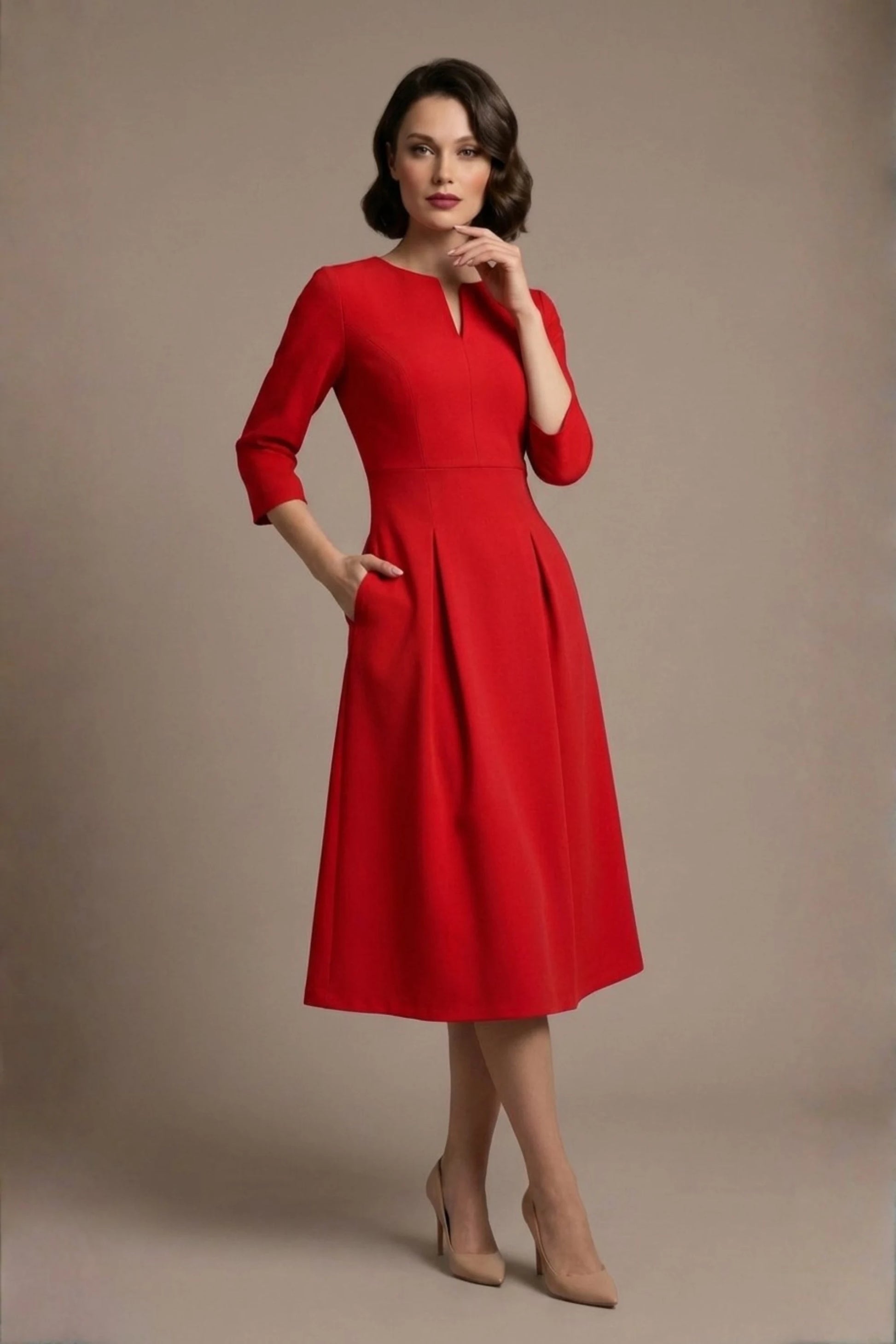 Woman wearing a diva catwalk Amanda Pleated a-line dress in a magenta pink colour against a beige background (Passion Red)