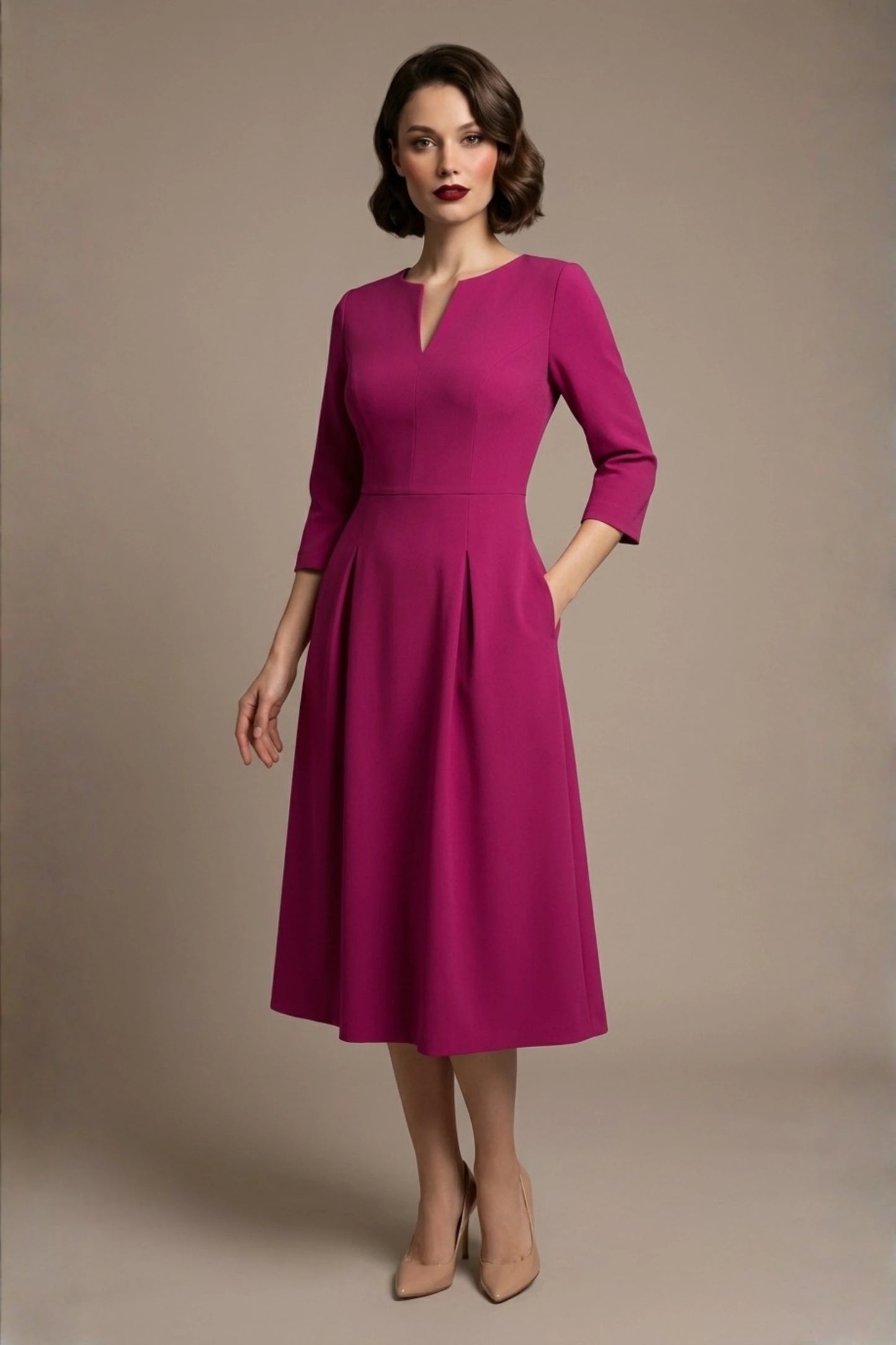 Woman wearing a diva catwalk Amanda Pleated a-line dress in a magenta pink colour with pockets against a beige background (Magenta)