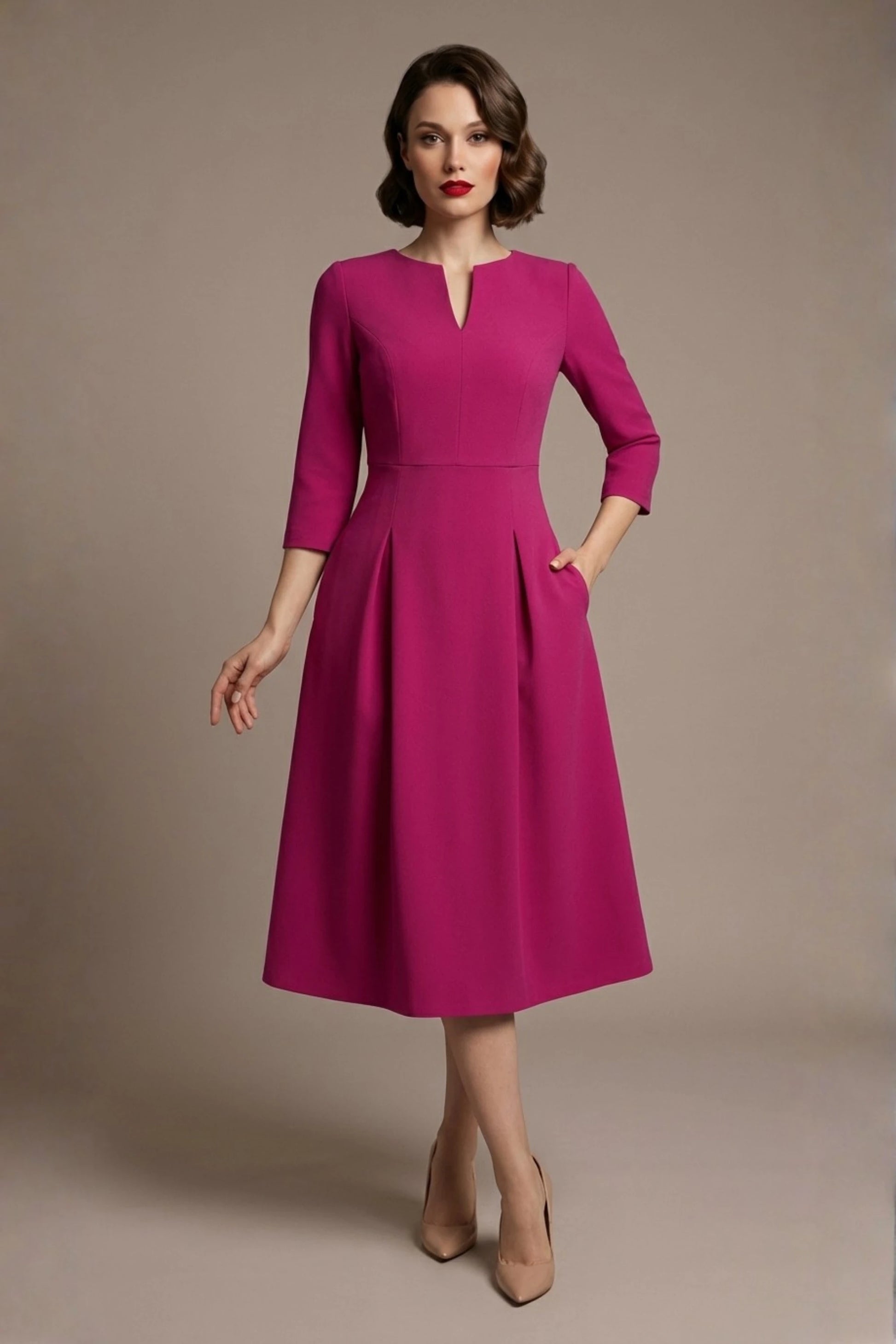 Woman wearing a diva catwalk Amanda Pleated a-line dress in a magenta pink colour with pockets against a beige background (Magenta)