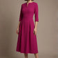Woman wearing a diva catwalk Amanda Pleated a-line dress in a magenta pink colour against a beige background (Magenta)