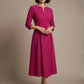 Woman wearing a diva catwalk Amanda Pleated a-line dress in a magenta pink colour against a beige background (Magenta)