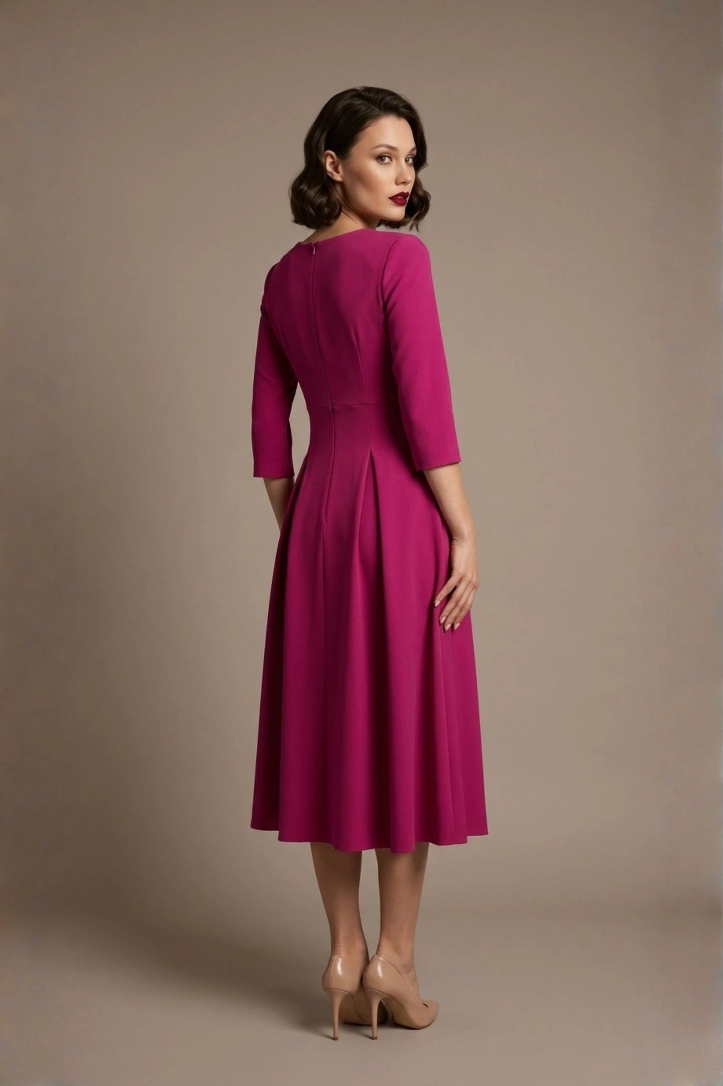 Woman wearing a diva catwalk Amanda Pleated a-line dress in a magenta pink colour against a beige background (Magenta)