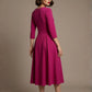 Woman wearing a diva catwalk Amanda Pleated a-line dress in a magenta pink colour against a beige background (Magenta)