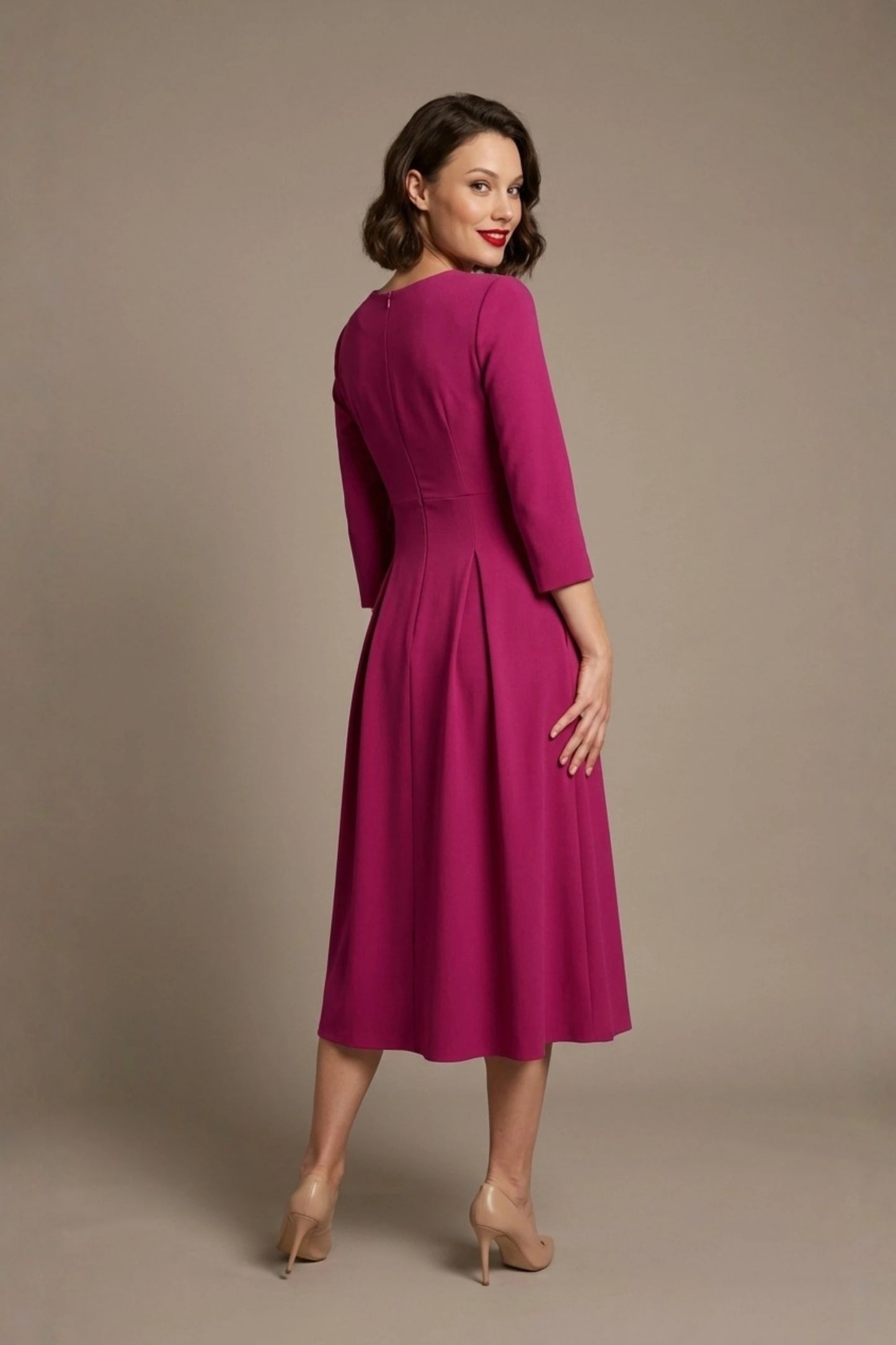 Woman wearing a diva catwalk Amanda Pleated a-line dress in a magenta pink colour against a beige background (Magenta)