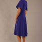 Side view Model wearing a diva catwalk Anders petal sleeve A-line dress against a plain background (Spectrum Indigo)