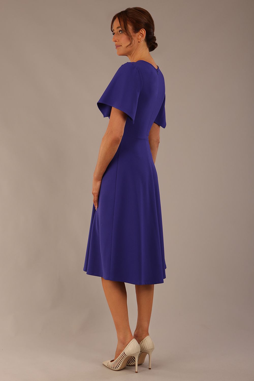 Side view Model wearing a diva catwalk Anders petal sleeve A-line dress against a plain background (Spectrum Indigo)