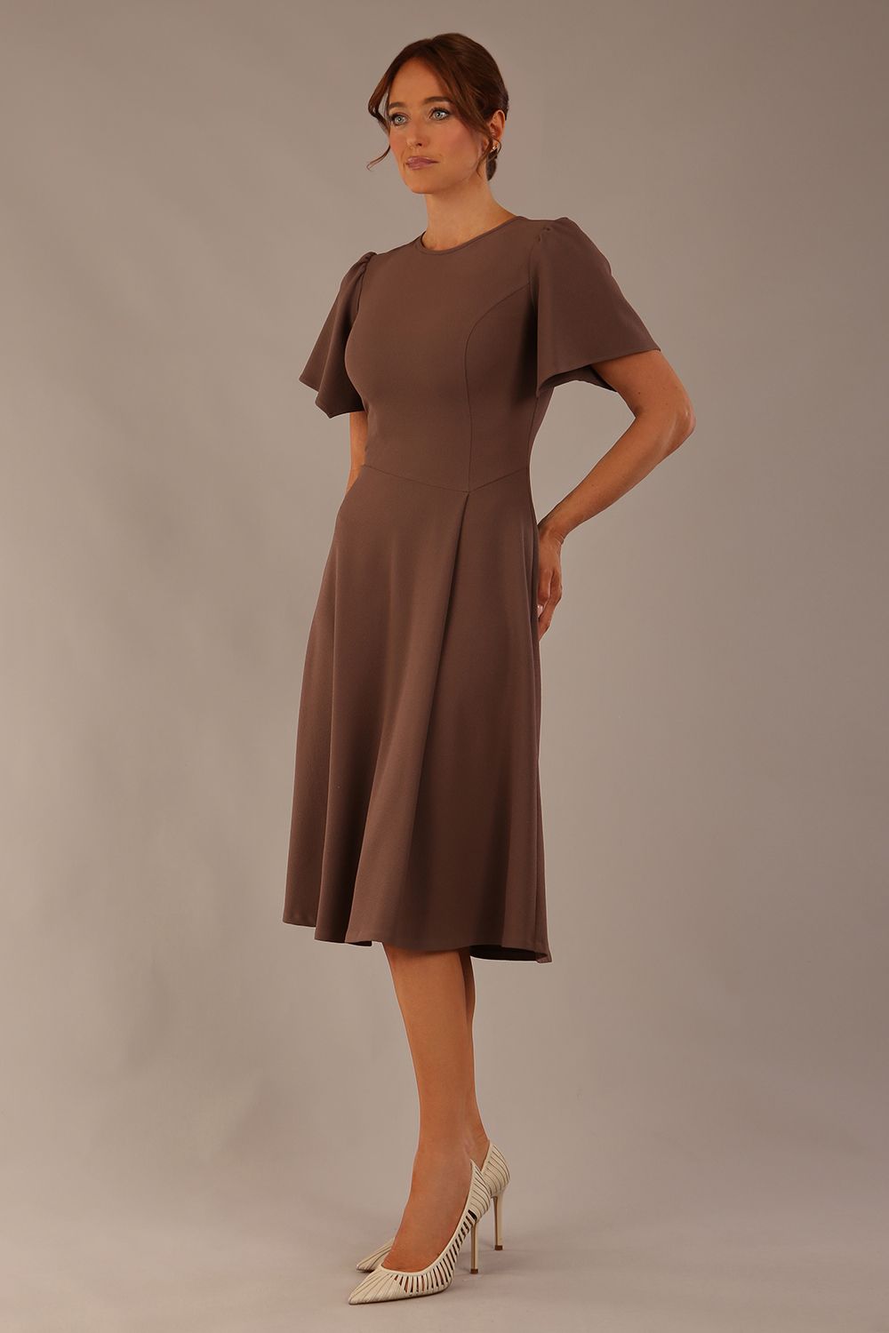 side view Model wearing a diva catwalk Anders petal sleeve A-line dress against a plain background (Peppercorn Brown)