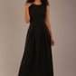 Model wearing the Cleo pleated midaxi dress in black with hands in the discreet side pockets.
