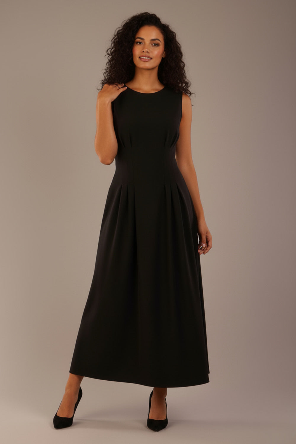 Model wearing the Cleo pleated midaxi dress in black with hands in the discreet side pockets.