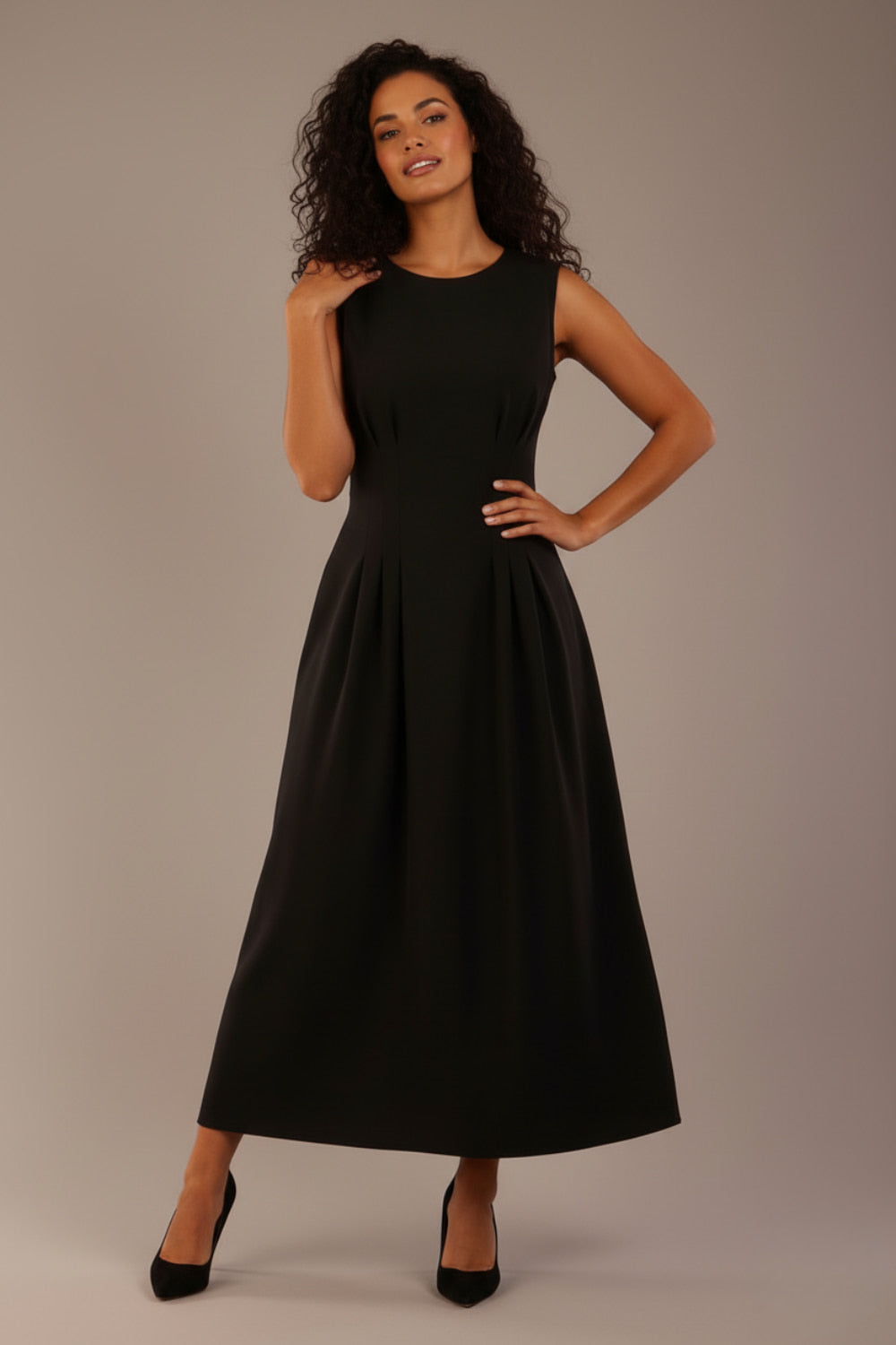 Model wearing the Cleo pleated midaxi dress in black with hands in the discreet side pockets.
