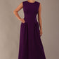 Model wearing the Cleo pleated midaxi dress in purple with hands in the discreet side pockets.