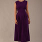 Model wearing the Cleo pleated midaxi dress in purple with hands in the discreet side pockets.