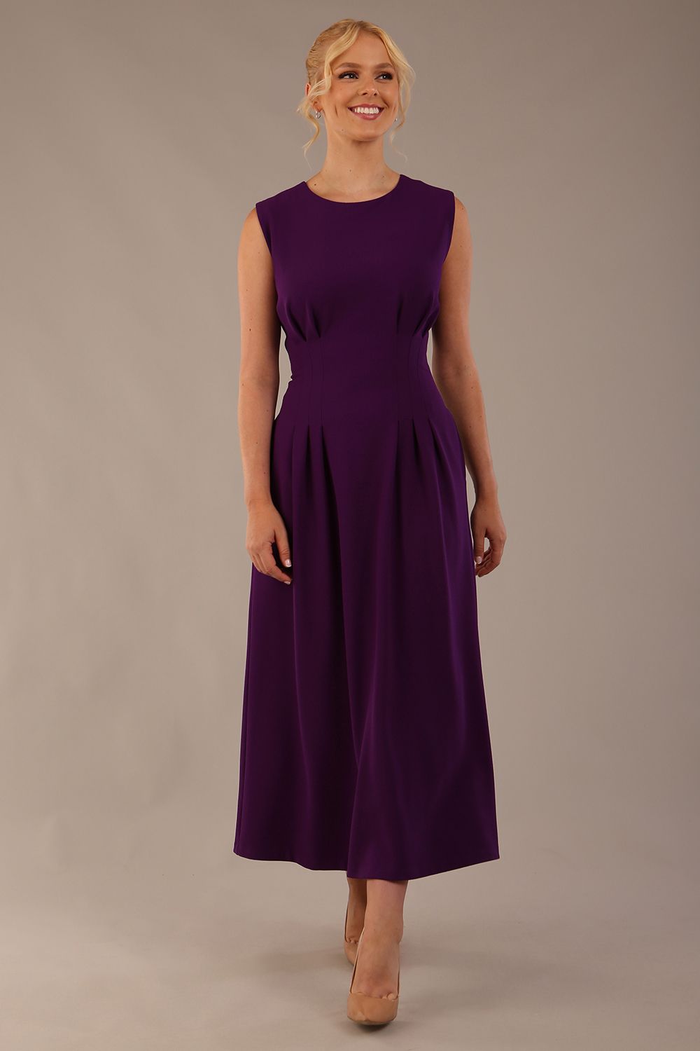 Model wearing the Cleo pleated midaxi dress in purple with hands in the discreet side pockets.