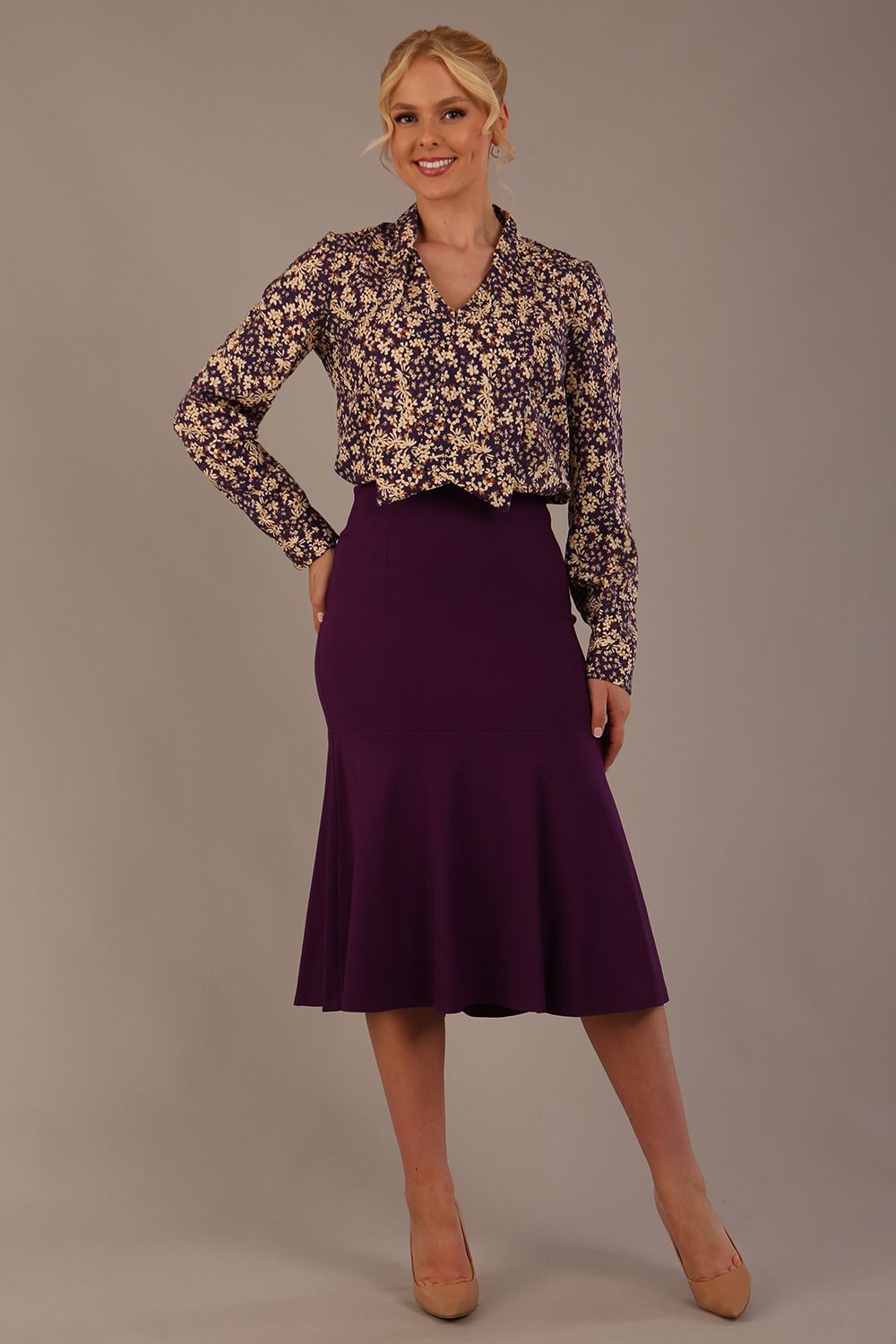Model wearing the Truro floral top, showing the standard hip-length and draped V-neck and purple marlene skirt against a gray background
