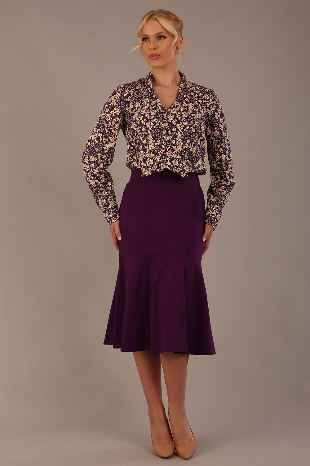 Model wearing the Truro floral top, showing the standard hip-length and draped V-neck and purple marlene skirt against a gray background