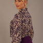 Model wearing the Truro floral top, showing the standard hip-length and draped V-neck and purple skirt against a beige background back view close up