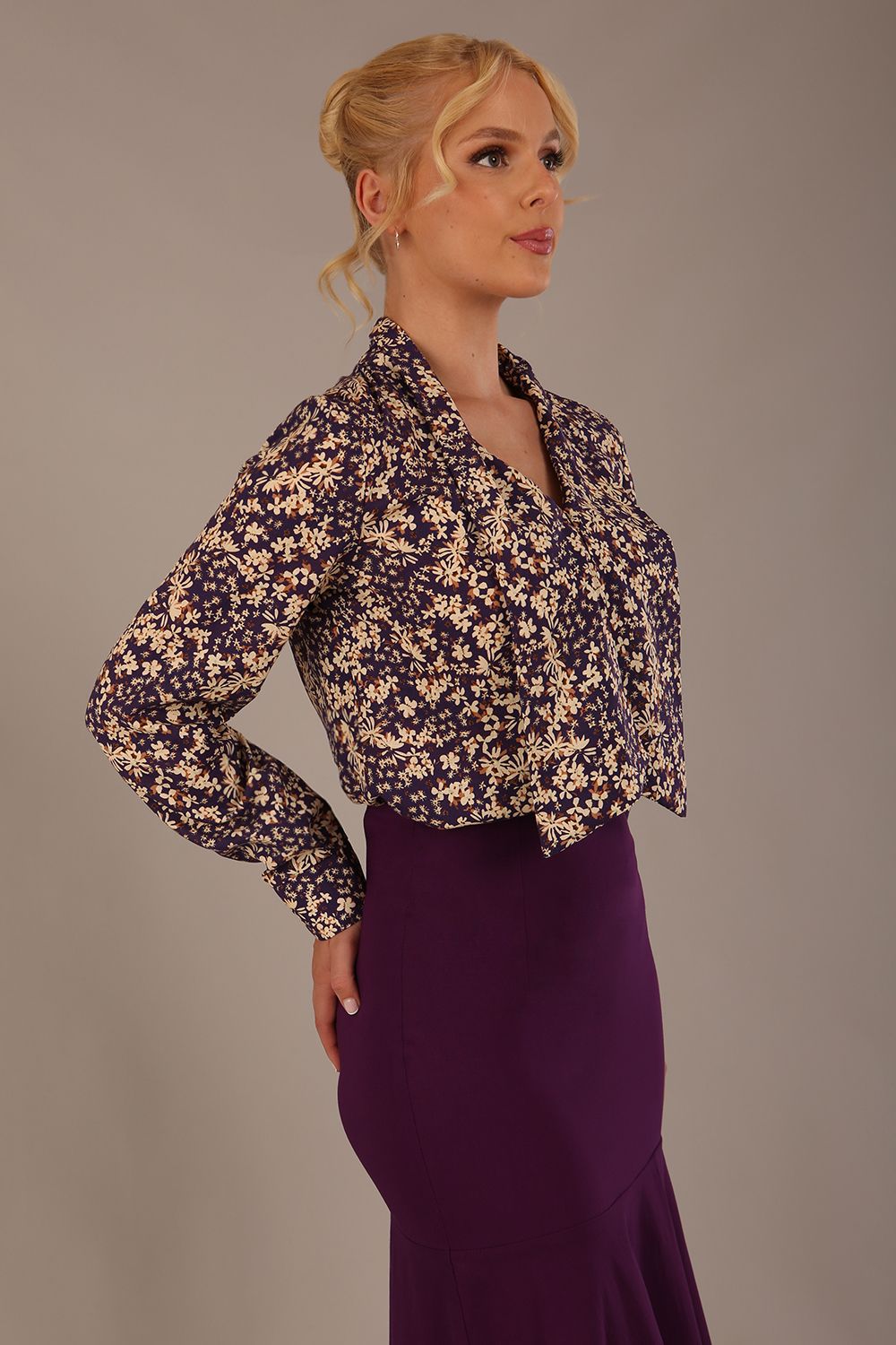 Model wearing the Truro floral top, showing the standard hip-length and draped V-neck and purple skirt against a beige background