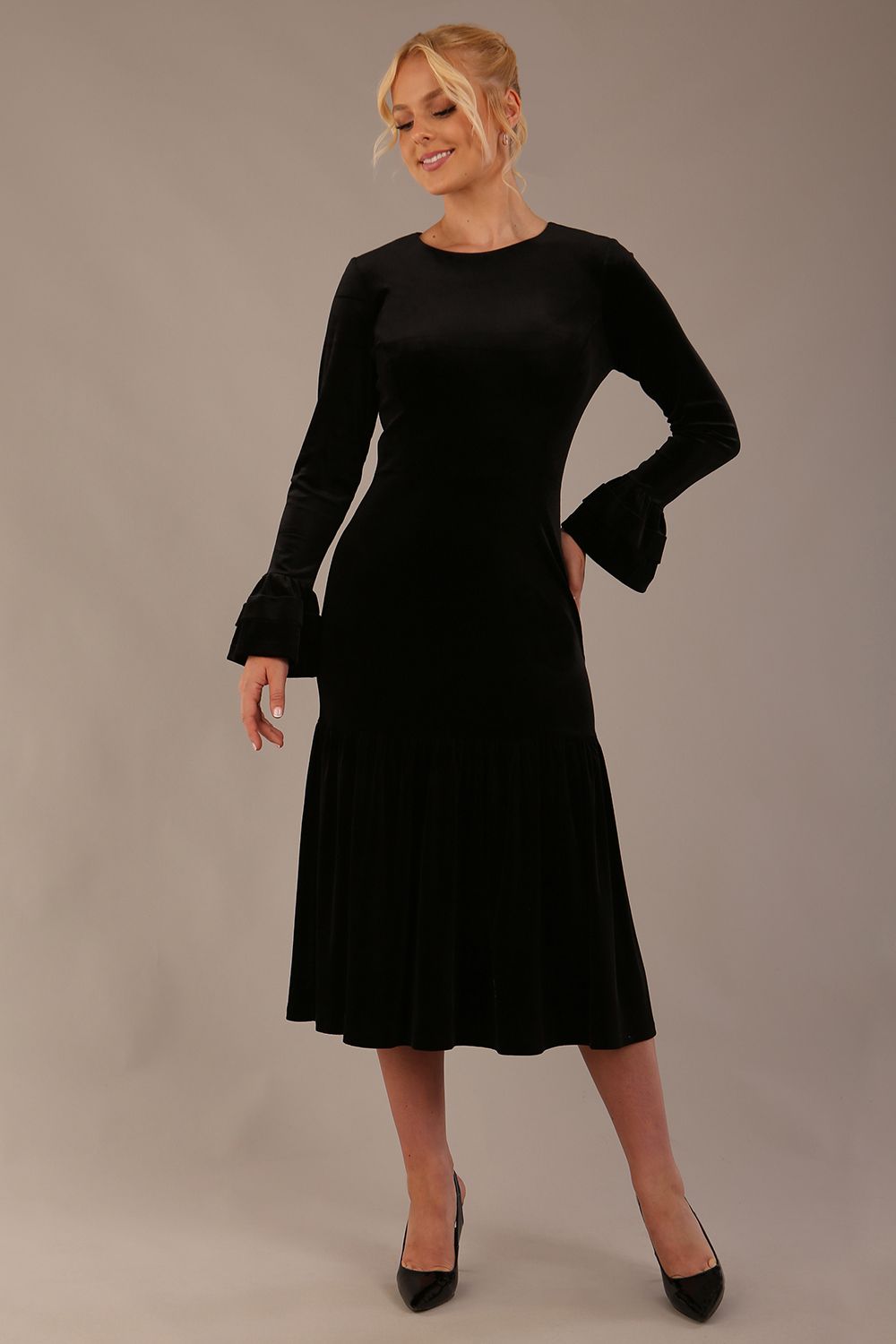 Model wearing the Sophisticat fluted sleeve velvet dress in black.
