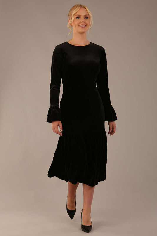 The Sophisticat black velvet dress shown in motion, highlighting the fluted fishtail skirt.