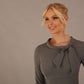 The model is wearing a diva catwalk Juliette 3/4 Sleeve Knee Length dress with bow detail in castlerock grey colour against a plain background close up