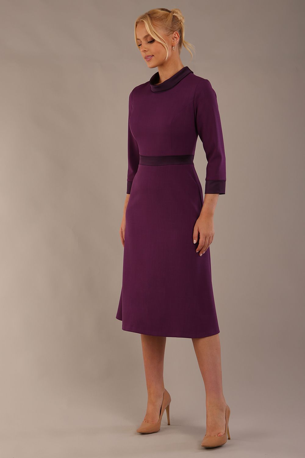 Model wearing the Sybil A-line midi dress in imperial purple with a satin cowl neck and waistband. (Imperial Purple)