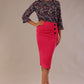 Brunette model wearing a fuchsia pink Claudette pencil skirt, showing the profile view with side buttons.