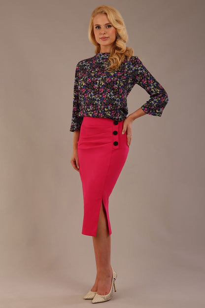 Blonde model wearing a fuchsia pink Claudette pencil skirt, showing the profile view with side buttons.