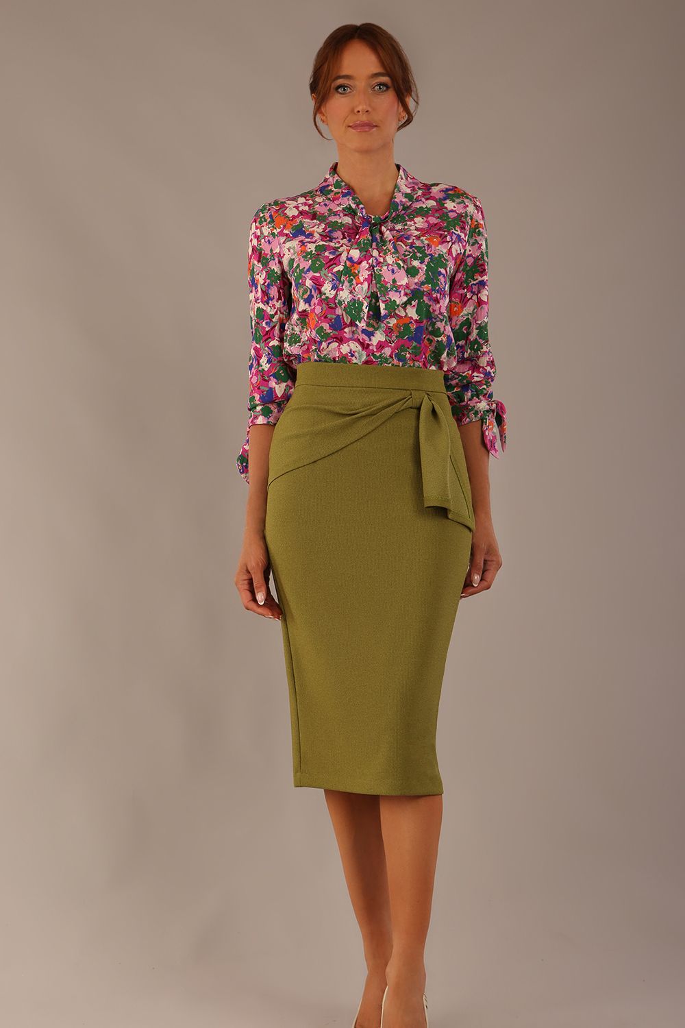 Model wearing a Radley Floral Tango print top with a central tie neckline and 3/4 sleeves, styled with an olive green skirt.
