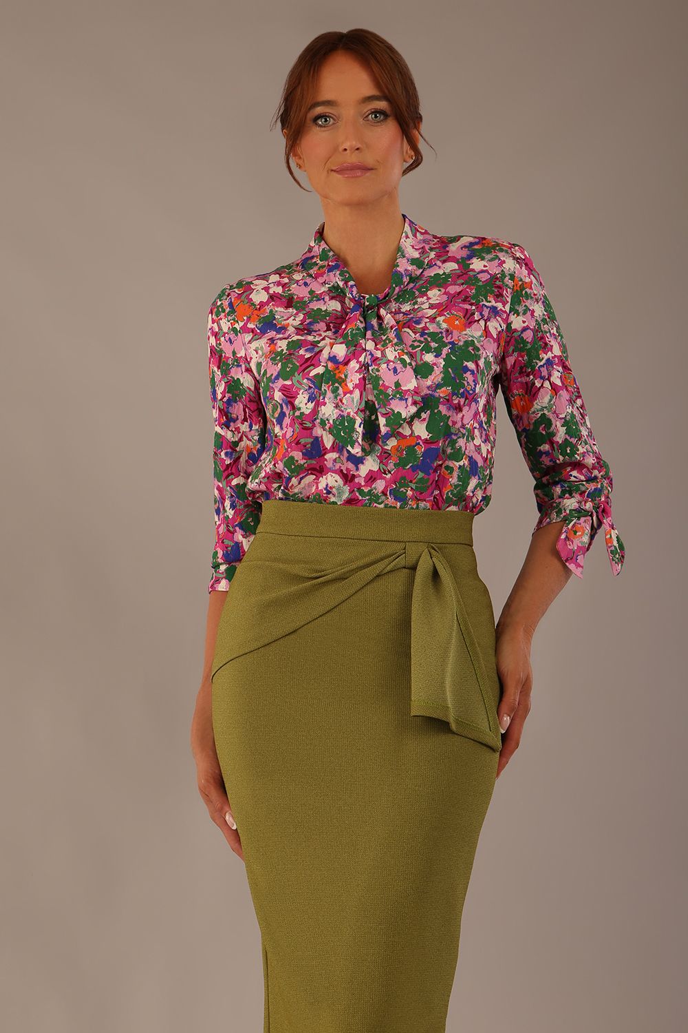 Model wearing a Radley Floral Tango print top with a central tie neckline and 3/4 sleeves, styled with an olive green skirt.