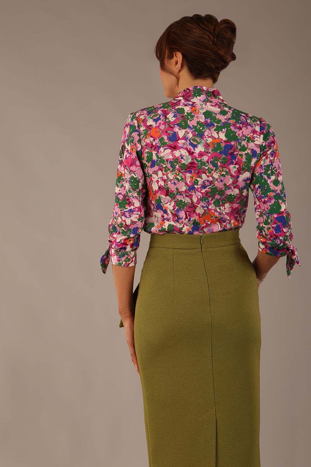 Model wearing a Radley Floral Tango print top with a central tie neckline and 3/4 sleeves, styled with an olive green skirt.
