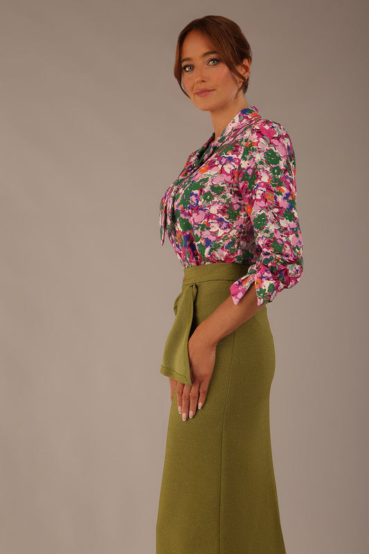 Model wearing a Radley Floral Tango print top with a central tie neckline and 3/4 sleeves, styled with an olive green skirt.
