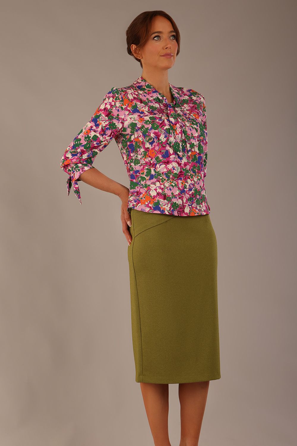 Model wearing a Radley Floral Tango print top with a central tie neckline and 3/4 sleeves, styled with an olive green skirt.