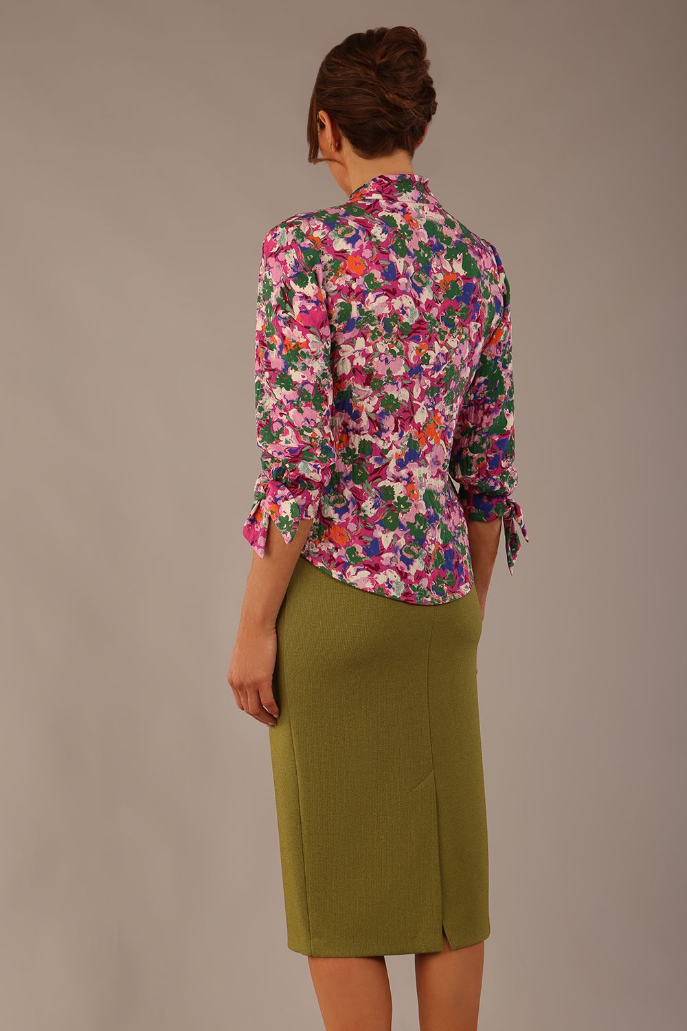 Model wearing a Radley Floral Tango print top with a central tie neckline and 3/4 sleeves, styled with an olive green skirt.