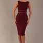 Woman wearing a The Rialto satin waist pencil dress in rich burgundy against a plain background