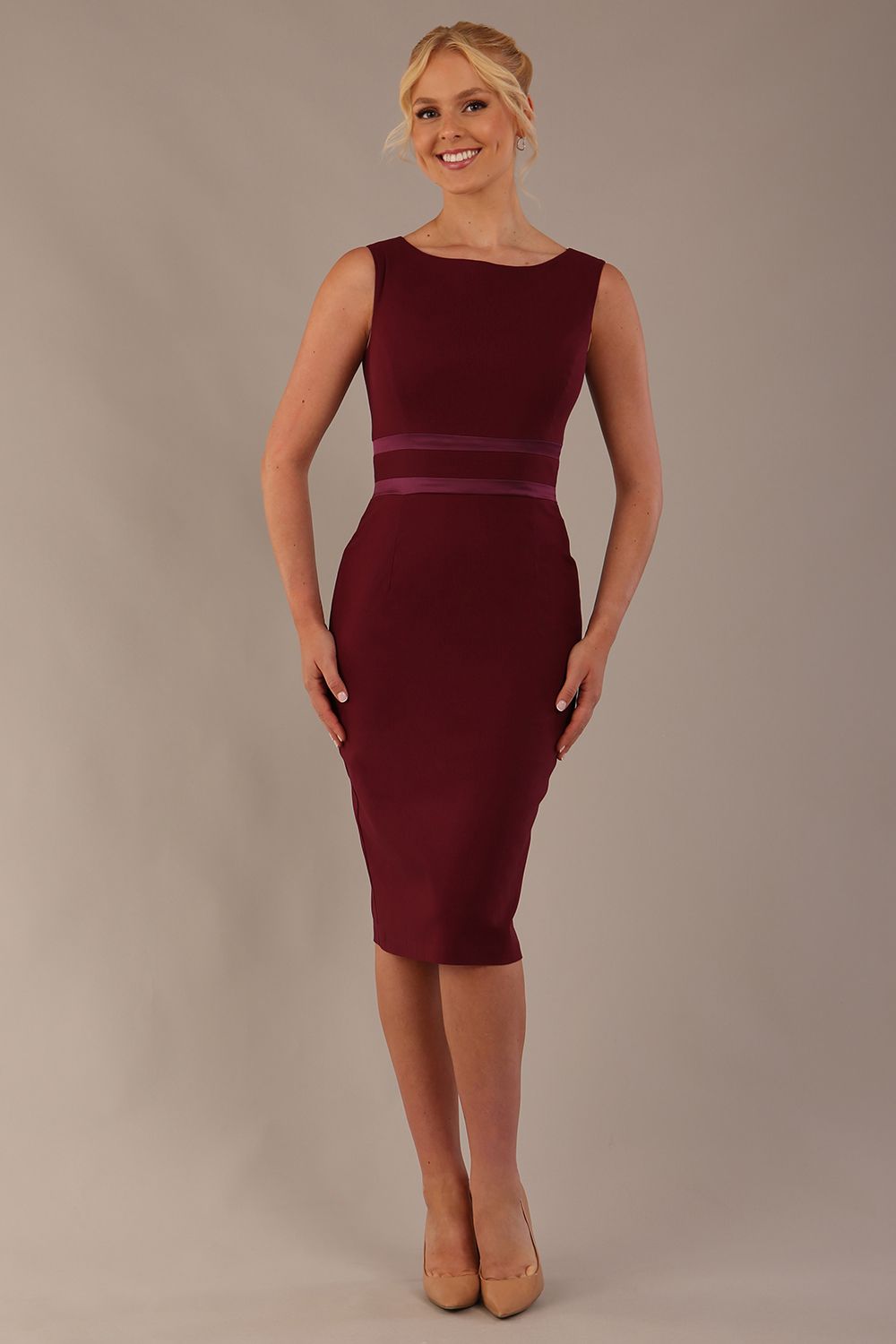 Woman wearing a The Rialto satin waist pencil dress in rich burgundy against a plain background