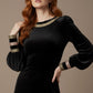 Woman wearing a black dress with gold accents on a beige background (Black Velvet with Sherwood Glitter Contrast)