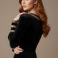 Woman wearing a black dress with sheer sleeves against a beige background  (Black Velvet with Sherwood Glitter Contrast)