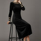 Woman wearing a black dress with gold accents sitting on a stool against a beige background (Black Velvet with Sherwood Glitter Contrast)
