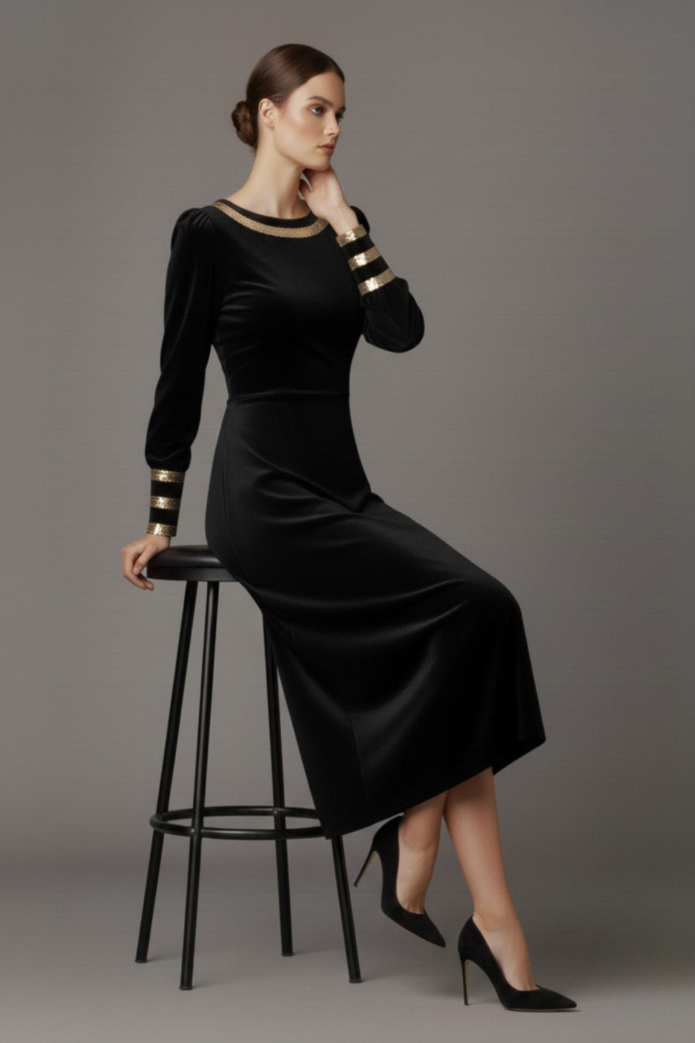 Woman wearing a black dress with gold accents sitting on a stool against a beige background (Black Velvet with Sherwood Glitter Contrast)