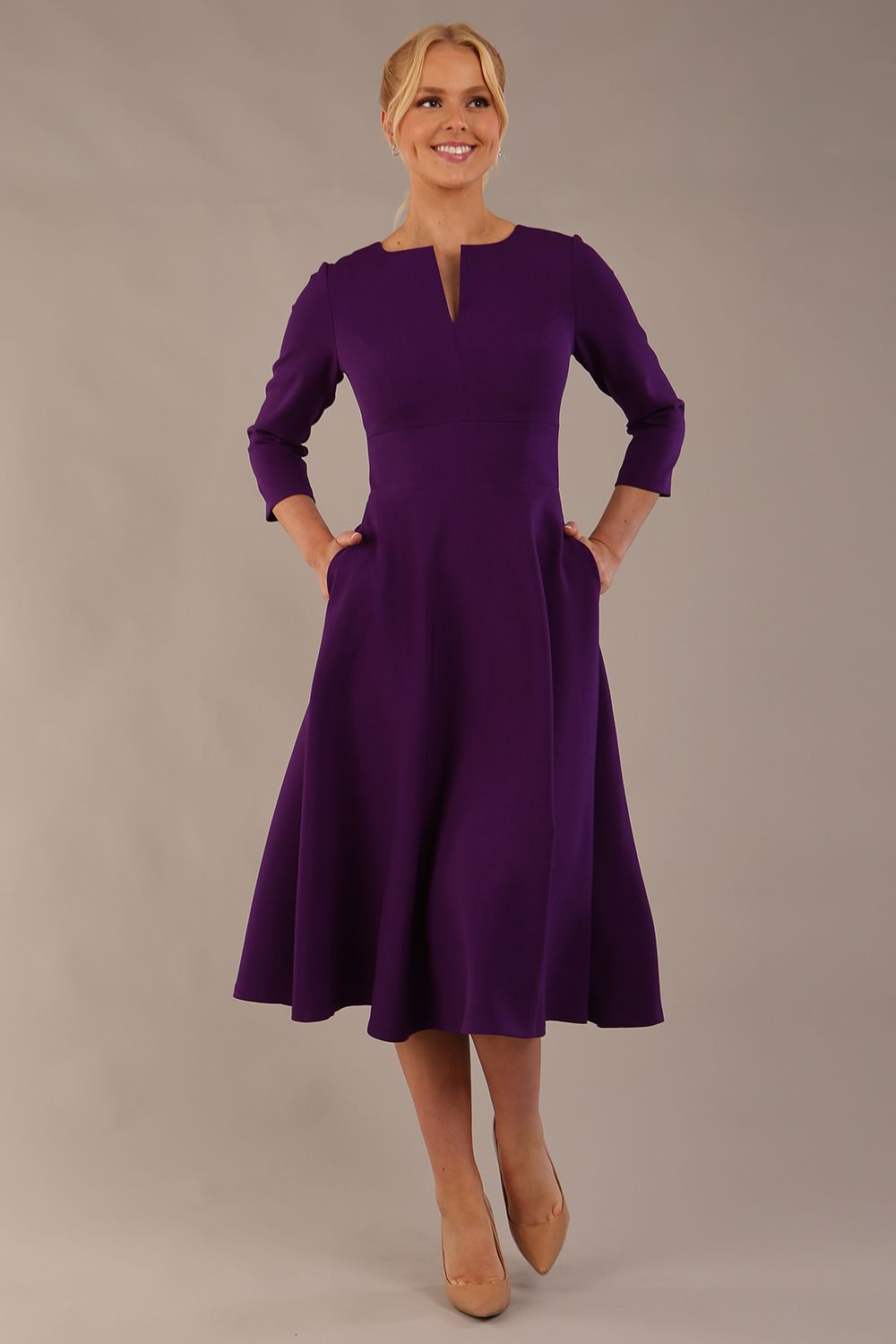 Model walking in the Perpetua A-line dress, highlighting the fluid skirt and V-slit neckline (Deep Purple)