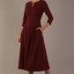 Model wearing the Perpetua A-line dress in wine with a hand in pocket (Wine)
